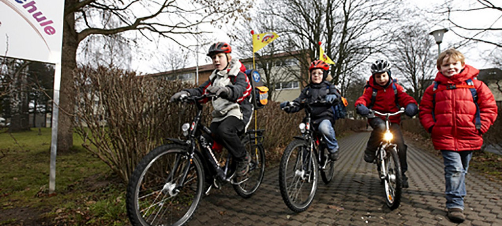 Kinder mit ihren Fahrrädern auf dem Weg zur Schule